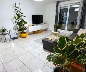 a living room with a couch and a tv at L'écrin du stade By UTA HOUSE in Saint-Denis