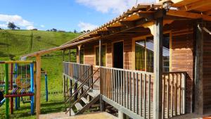 a wooden cabin with a porch and a playground at Finca Severo Refugio in Zipaquirá