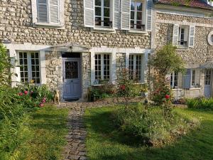 uma casa de pedra com uma porta azul e um cão no quintal em Avenue du Château em Saint-Just