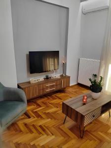 salon z telewizorem i drewnianą podłogą w obiekcie Εlite Αpartment Trikala w mieście Tríkala