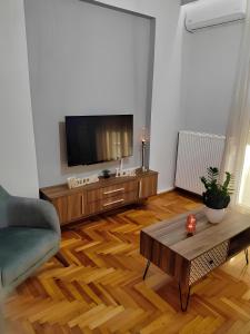 a living room with a television and a wooden floor at Εlite Αpartment Trikala in Tríkala