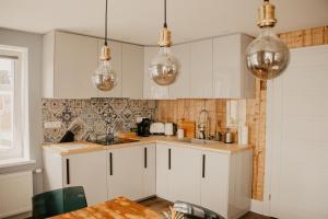 una cocina con armarios blancos y luces de plata en Vītola apartamenti en Kuldīga