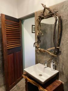 uma casa de banho com um lavatório branco e um espelho. em Jardin d'Ulysse & Hard Rock em Morjim