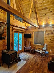 una sala de estar con estufa de leña en una cabaña en Neshannock Creekside Log Cabin, en Volant