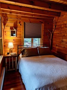 1 dormitorio con 1 cama en una cabaña de madera en Neshannock Creekside Log Cabin, en Volant