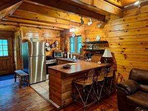 a kitchen with wooden walls and a refrigerator and a counter at Neshannock Creekside Log Cabin in Volant
