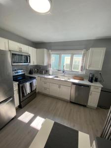 una cocina con armarios blancos y electrodomésticos de acero inoxidable en Luxury 3 bdr apt with backyard and off-street parking, en Watertown