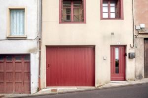 - deux portes de garage rouges sur le côté d'un bâtiment dans l'établissement Le Charme de la Verrière, à Thiers