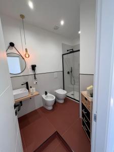 La salle de bains est pourvue de 2 toilettes, d'un lavabo et d'une douche. dans l'établissement Valguarnera Studio Apartments, à Palerme