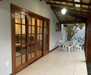 d'une terrasse avec des portes en bois, une table et des chaises. dans l'établissement Casa Paris 481 - Sua Mansão na Praia do Morro, à Guarapari