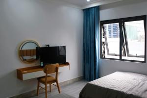 una camera da letto con scrivania, letto e specchio di Royal Homestay - Royal Center a Móng Cái