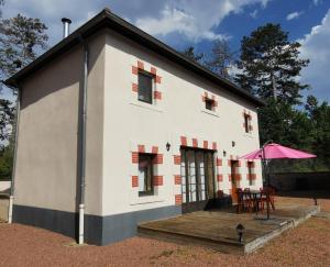 een klein wit huis met een tafel en een roze paraplu bij Cottage Trève Raisin in Perreux