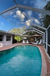 Greenacres CityThe Utopia Resort Dream Pool BBQ Outdoor Dining的游泳池设有带遮阳篷的户外庭院