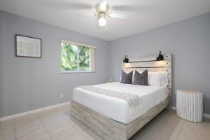 Greenacres CityThe Utopia Resort Dream Pool BBQ Outdoor Dining的卧室配有白色的床和吊扇 更多41张照片