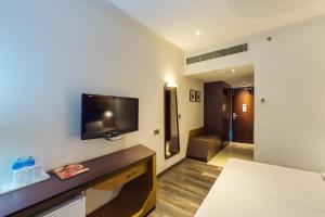 a hotel room with a tv on a wall at Hotel Indraprastha in Palakkad