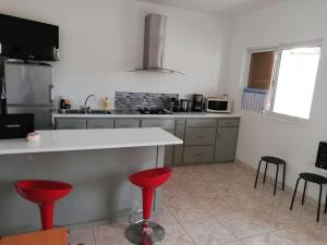 a kitchen with a counter and red stools in it at Casa Yô in Mindelo