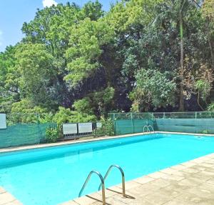 an empty swimming pool with trees in the background at Appartement cosy dans résidence avec piscine in Fort-de-France