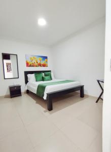 a bedroom with a bed with green pillows at Hotel Orquídea Real in Valledupar