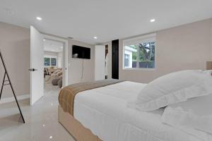 a white bedroom with a large bed and a television at Casa Copal: Relaxing Beach House in Hollywood