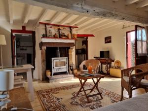 Petite maison Normande في Bellou-en-Houlme: غرفة معيشة مع موقد وطاولة