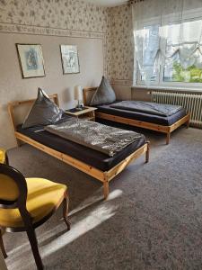 1 dormitorio con 2 camas, silla y ventana en Gästehaus3land in Weil am Rhein, en Weil am Rhein