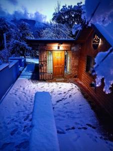 Una casa con una puerta en la nieve por la noche en Cuatro Cerros Hostel en San Carlos de Bariloche