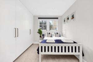 a white bedroom with a bed and a window at Luxury 3 bedroom house in Limehouse, close to city! Sleeps 6-8! in London