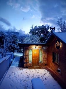 a house with snow on the ground in front of it at Cuatro Cerros Hostel in San Carlos de Bariloche