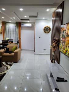ein Wohnzimmer mit einem Sofa und einer Uhr an der Wand in der Unterkunft Home away from home #1 in Accra