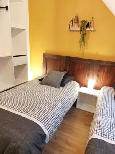 a bedroom with two beds and a yellow wall at Chez Virginie in Ornans