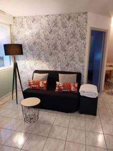 a living room with a black couch and a table at Chez Virginie in Ornans