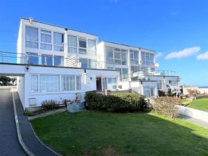 a large white house with a lawn in front of it at Newquay Fistral Beach View with pool in Newquay