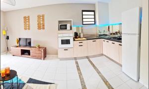 Appartement cosy dans résidence avec piscine في فورت-دو-فرانس: مطبخ مع دواليب بيضاء وثلاجة