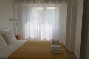 una camera da letto con un grande letto con asciugamani di Apartamento muito central - 300 metros da Praia a Costa da Caparica