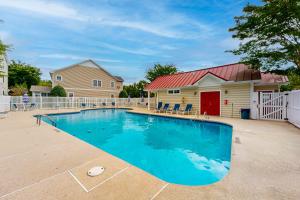 a swimming pool in front of a house with a red roof at Oyster Bay Villas --- 20411 Jeb Dr, Unit #36 in Rehoboth Beach