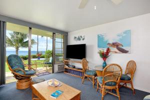 a living room with a table and chairs and a television at Maalaea Banyans 113 in Maalaea