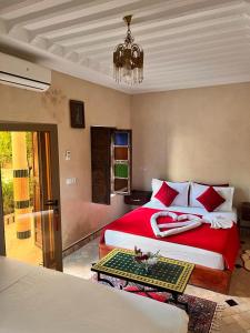 een slaapkamer met een rood bed en een kroonluchter bij Riad Rime Garden Marrakech in Marrakesh