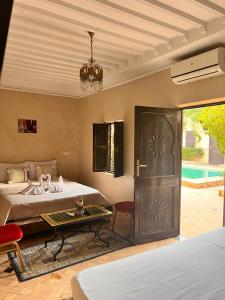 una camera con due letti, un tavolo e una porta di Riad Rime Garden Marrakech a Marrakech