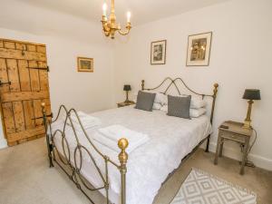 Schlafzimmer mit einem Bett mit weißer Bettwäsche und einem Kronleuchter in der Unterkunft Queens Cottage in Much Wenlock