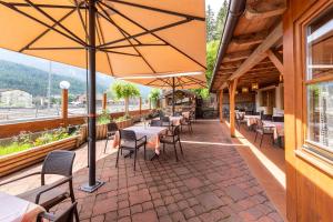 un restaurant avec des tables, des chaises et un parasol dans l'établissement Hotel Walter, à San Candido