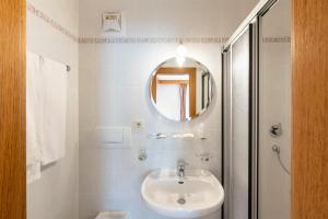 La salle de bains blanche est pourvue d'un lavabo et d'un miroir. dans l'établissement Hotel Walter, à San Candido