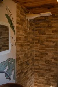 y baño con ducha y pared de ladrillo. en Espaço Cultural Lotus - Suítes, Hostel e Camping, en Alto Paraíso de Goiás