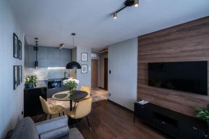 a living room with a table and a large television at Noche Apartamenty Premium in Biała Podlaska