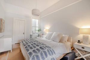 a white bedroom with a large bed and a desk at Charming Victorian Oasis with an Elegant and Spacious Haven in San Francisco