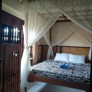 a bedroom with a canopy bed with a blue item on it at Pondok Bulan Mas in Ubud
