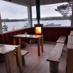 a room with benches and a stove with a view of a lake at Sevetin Baari & Guesthouse in Sevettijärvi