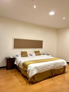 um quarto com uma cama grande e piso em madeira em ركن داري للشقق المخدومة em Al Majmaah