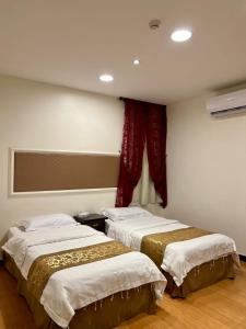 um quarto com 2 camas e uma janela com cortinas vermelhas em ركن داري للشقق المخدومة em Al Majmaah