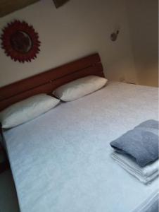 1 cama con sábanas y almohadas blancas y espejo en B&B L'Alba, en Gagliato
