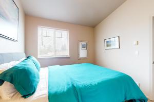 a bedroom with a bed with blue sheets and a window at Siuslaw Sanctuary in Florence
